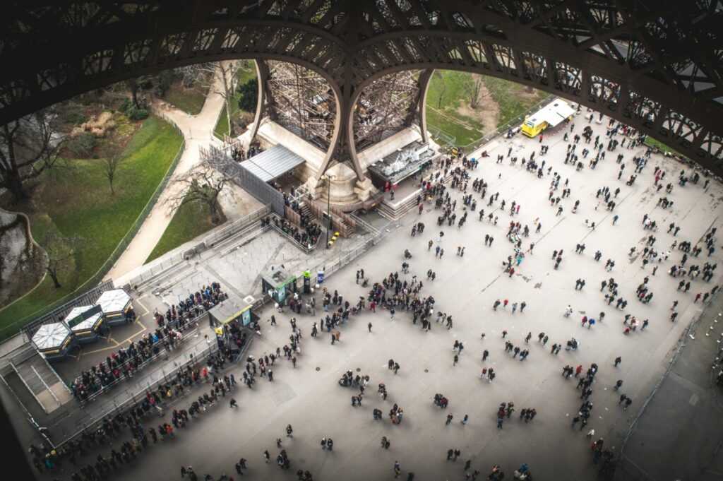 Crowds of people waiting in line at the base of the Eiffel Tower in Paris