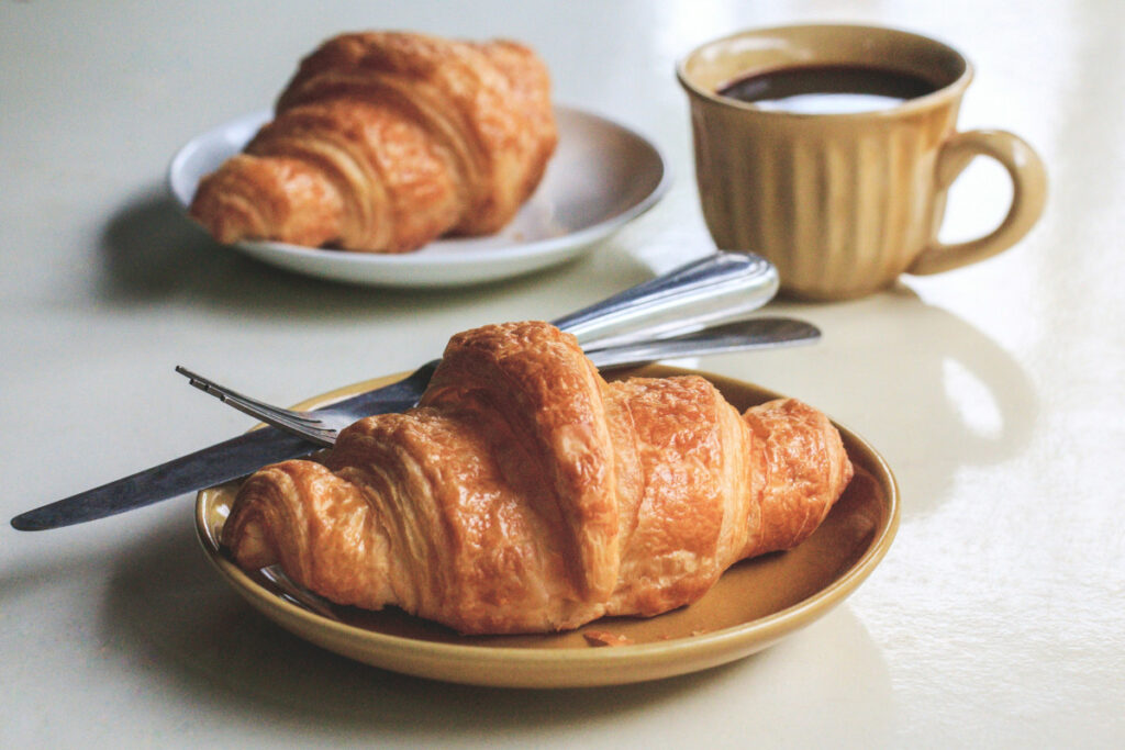 French croissant on a plate with a coffee